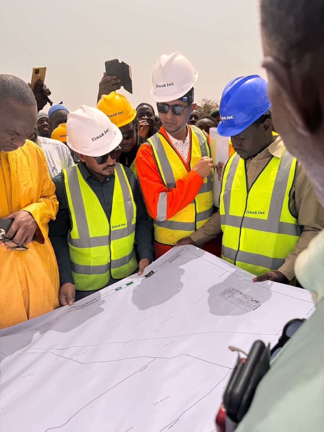 Project team reviewing a site plan laid out on the ground