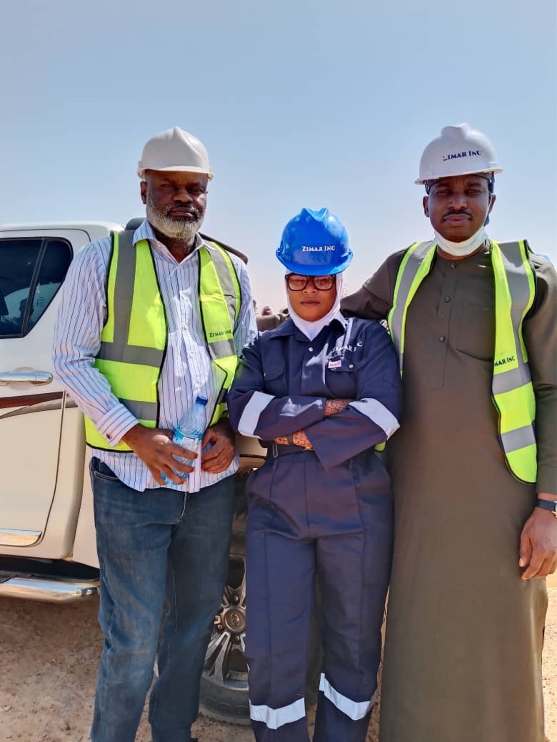 Three project team members in hi-vis vests and hard hats on site